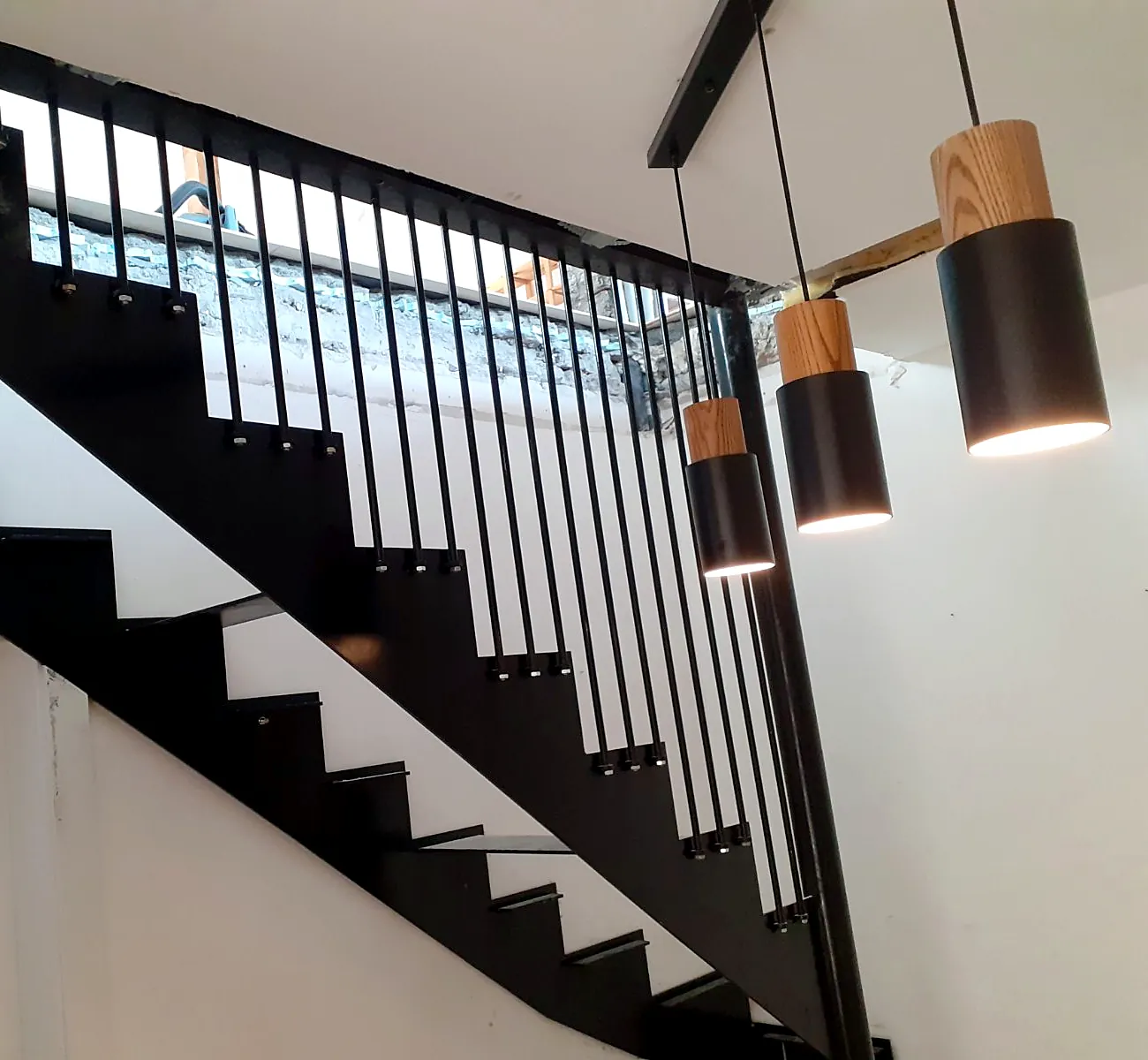 Schwarze Stahltreppe mit lasergeschnittenen Wangen und angeschraubtem senkrechtem Stabgeländer